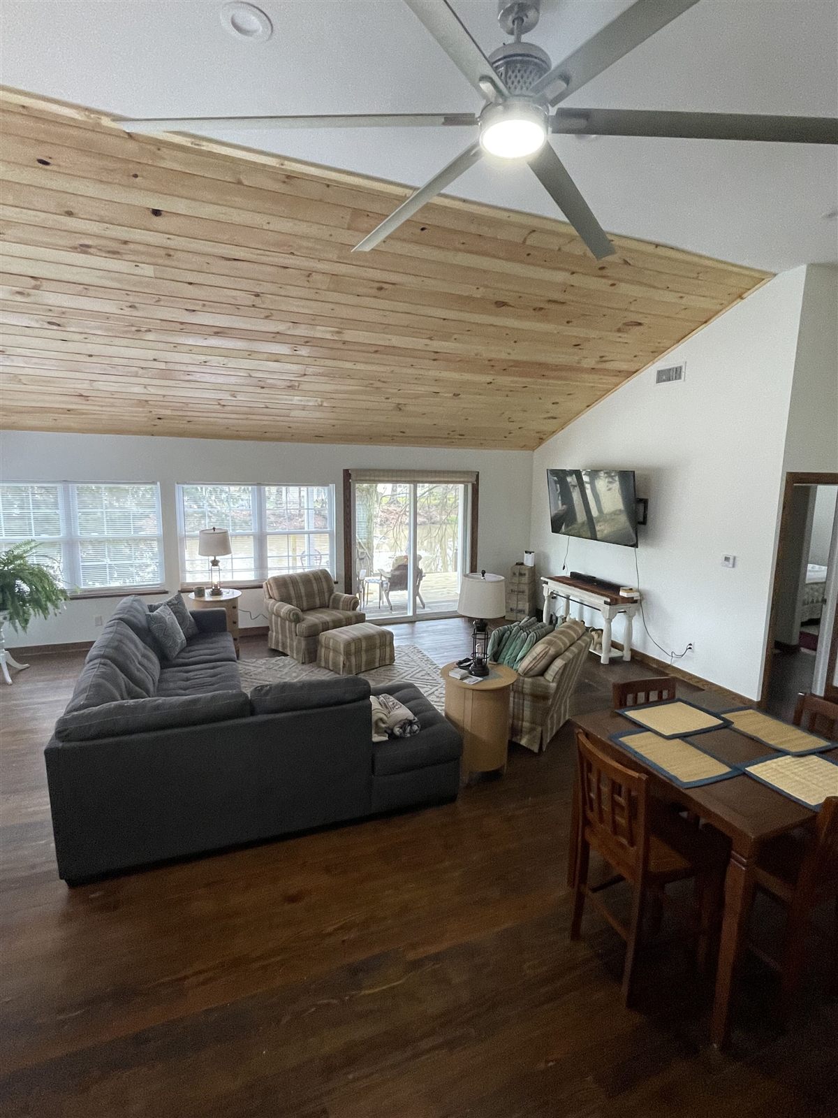Living room with sectional sofa, plaid armchairs, and sliding doors out to the river deck