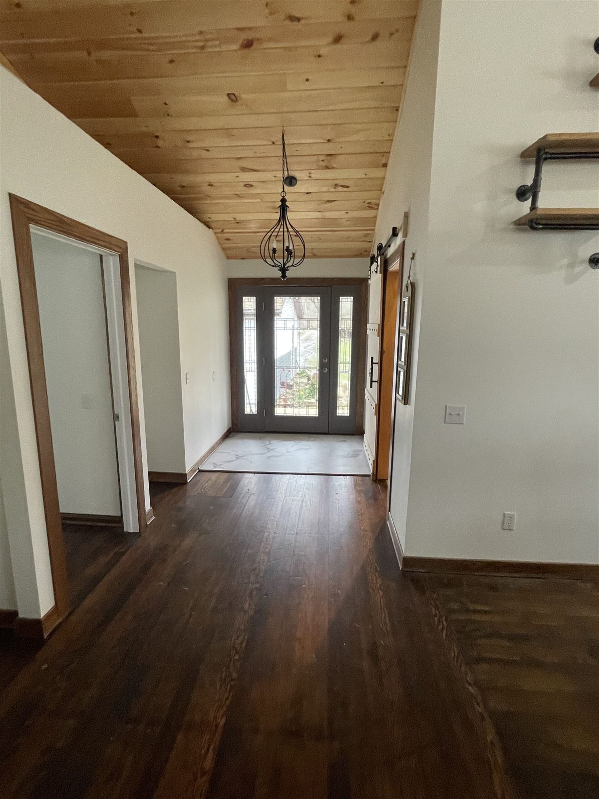 Entry hall with glass-paneled front door, sliding barn door, and wood-plank ceiling
