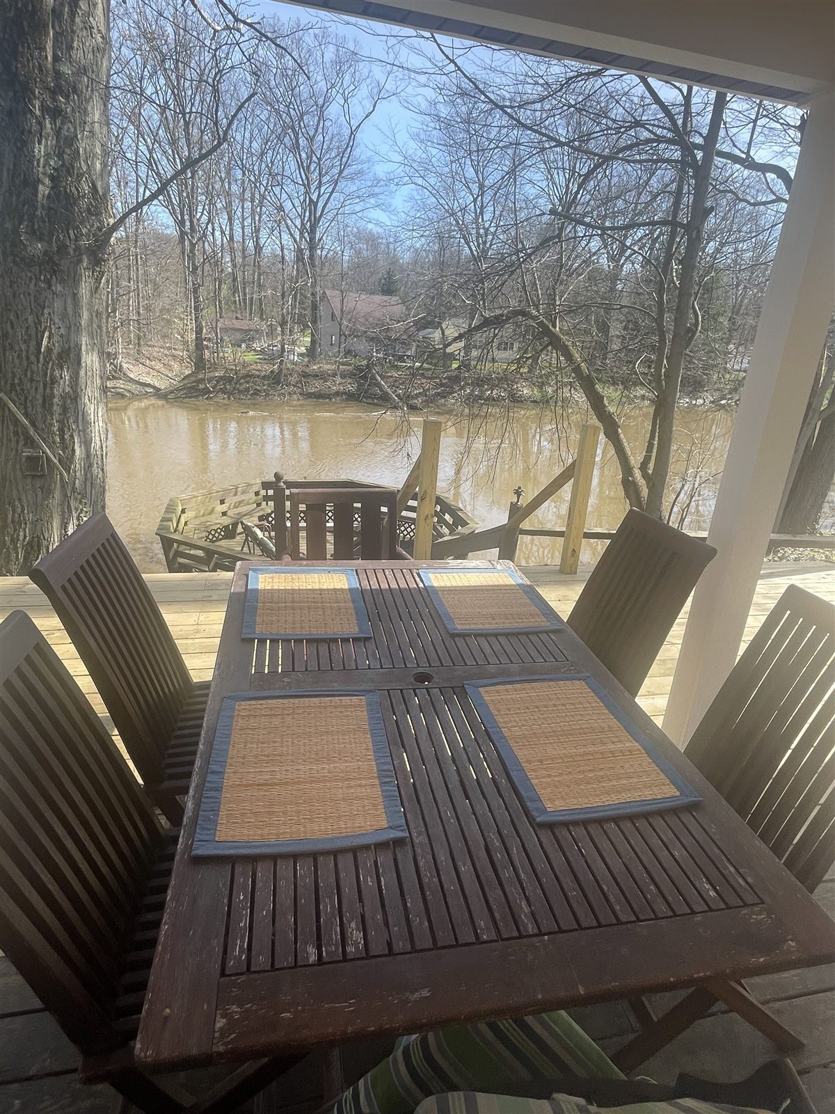 Outdoor dining table on the covered deck, with the Grand River and dock steps below